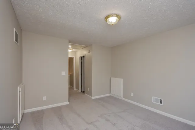 a view of an empty room with closet and a window