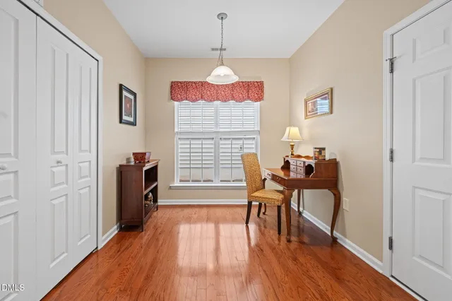 a dining room with wooden floor a chandelier a wooden table and chairs