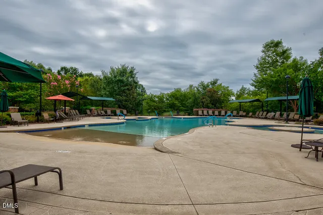 a view of swimming pool with seating area and trees in the background