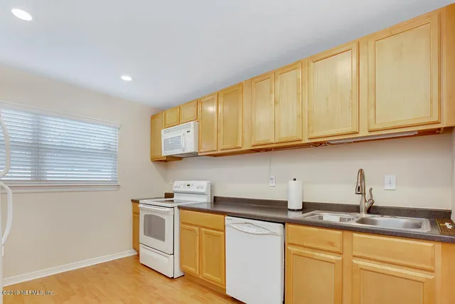a kitchen with stainless steel appliances granite countertop a sink and cabinets with wooden floor