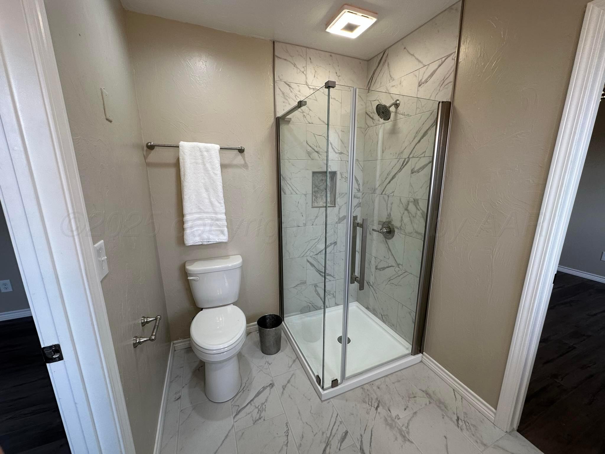 4402 Gary Lane Amarillo, TX 79110 - Photo 14 of 19 a bathroom with a glass door shower and toilet