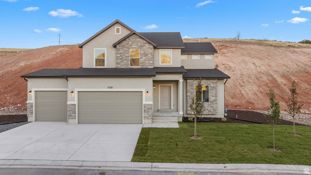 View of front of home with stone siding, stucco siding, driveway, and a front lawn