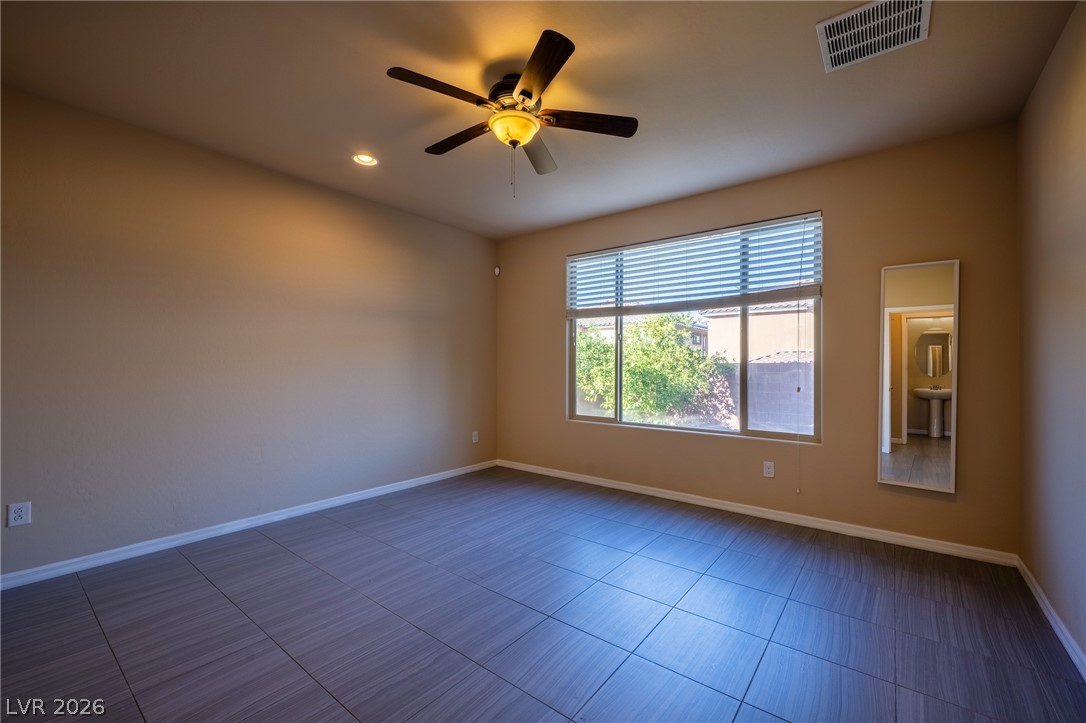 11016 Prairie Grove Road Las Vegas, NV 89179 - Photo 15 of 37 Well-lit room featuring tile flooring and a ceiling fan, offering a clear window view of lush greenery.
