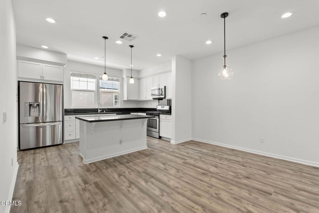 3705 Islander Walk Oxnard, CA 93035 - Photo 7 of 45 a large kitchen with stainless steel appliances a large counter top a sink a refrigerator and a window