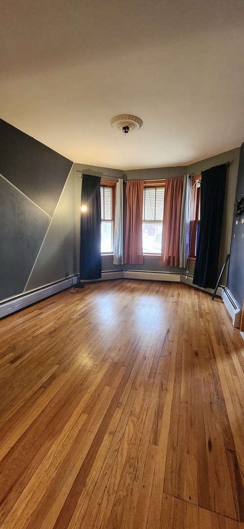 4450 West Altgeld Street, Unit 1 Chicago, IL 60639 - Photo 6 of 29 an empty room with wooden floor and windows