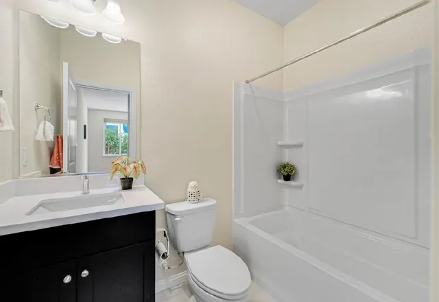 a bathroom with a granite countertop bathtub shower sink vanity and toilet