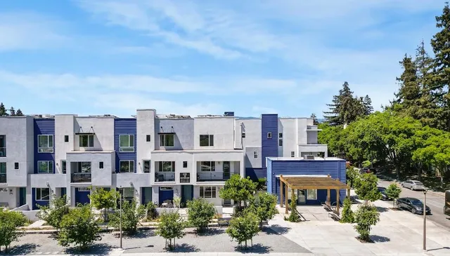 a view of a building with a lot of plants and trees around