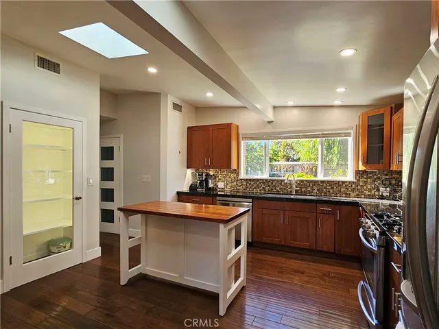 a kitchen with granite countertop a stove a sink and a refrigerator