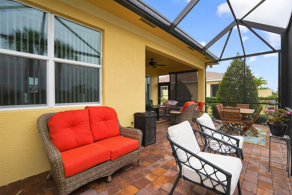 21044 Southwest Modena Way Port St. Lucie, FL 34986 - Photo 37 of 42 a view of a patio with couches table and chairs under an umbrella