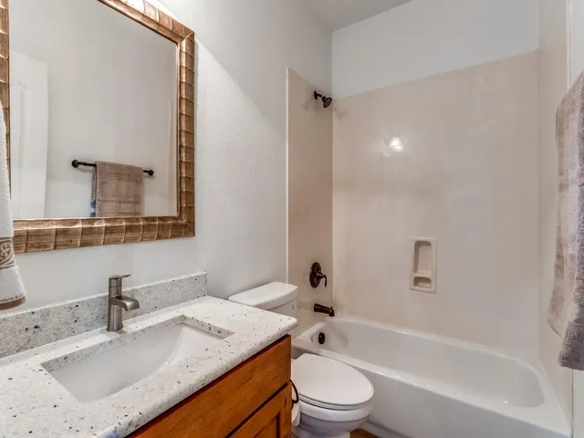 a bathroom with a granite countertop sink a toilet and bathtub