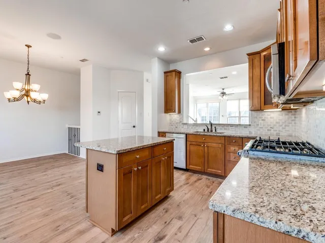 a kitchen with stainless steel appliances granite countertop a stove a sink and a microwave