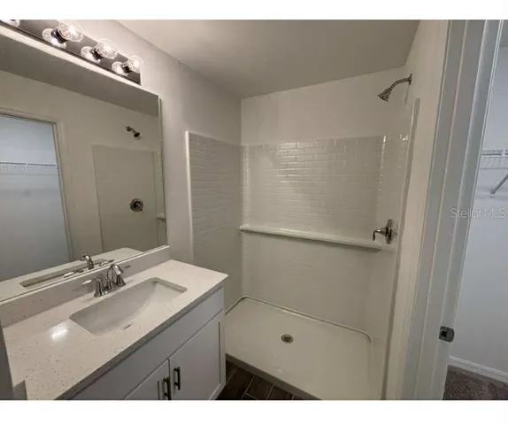 a bathroom with a sink shower and a mirror