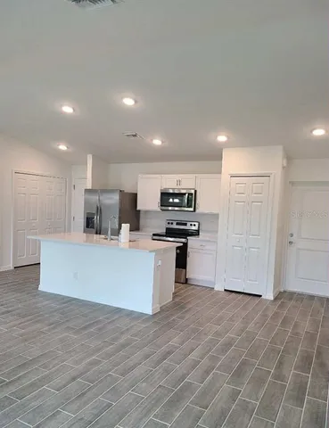 a large kitchen with stainless steel appliances kitchen island a large counter top and a stove top oven