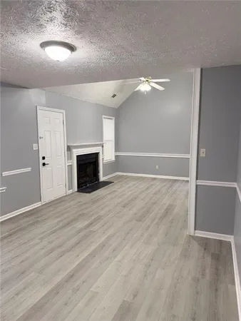 an empty room with wooden floor fireplace and windows