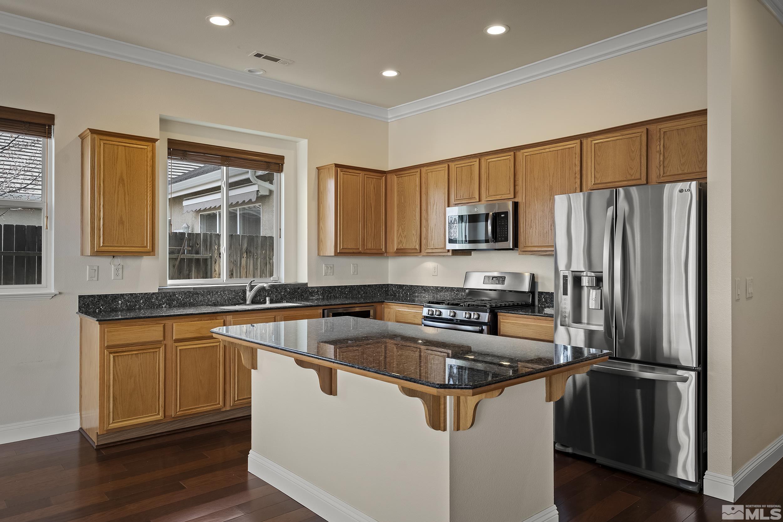 1575 Wyatt Court Reno, NV 89521 - Photo 12 of 40 a kitchen with stainless steel appliances granite countertop a refrigerator a sink a stove a microwave and wooden floors