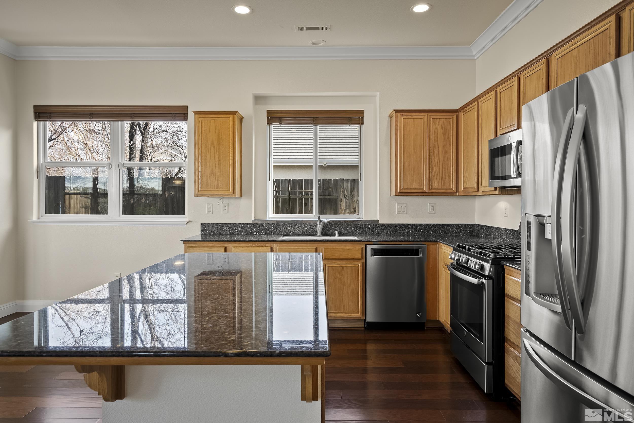 1575 Wyatt Court Reno, NV 89521 - Photo 14 of 40 a kitchen with stainless steel appliances granite countertop a refrigerator a stove and a sink with wooden floor