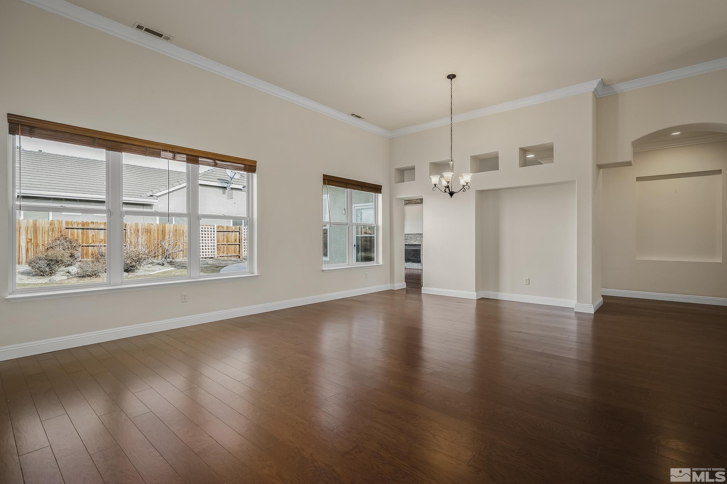 1575 Wyatt Court Reno, NV 89521 - Photo 4 of 40 an empty room with wooden floor chandelier and windows