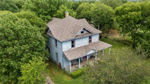 an aerial view of a house with swimming pool and large trees