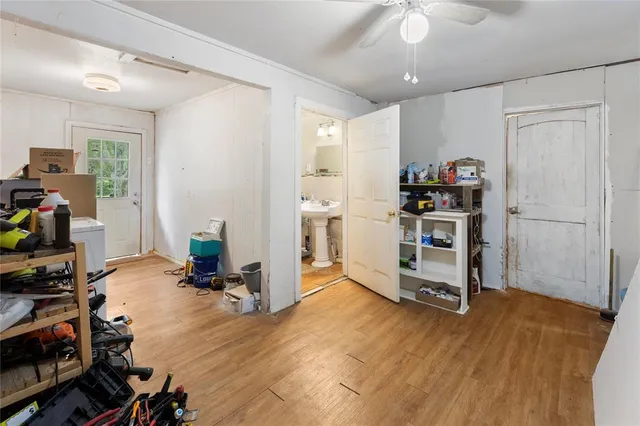 an empty room with wooden floor chandelier fan and windows