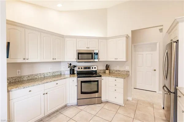 a kitchen with white cabinets and appliances