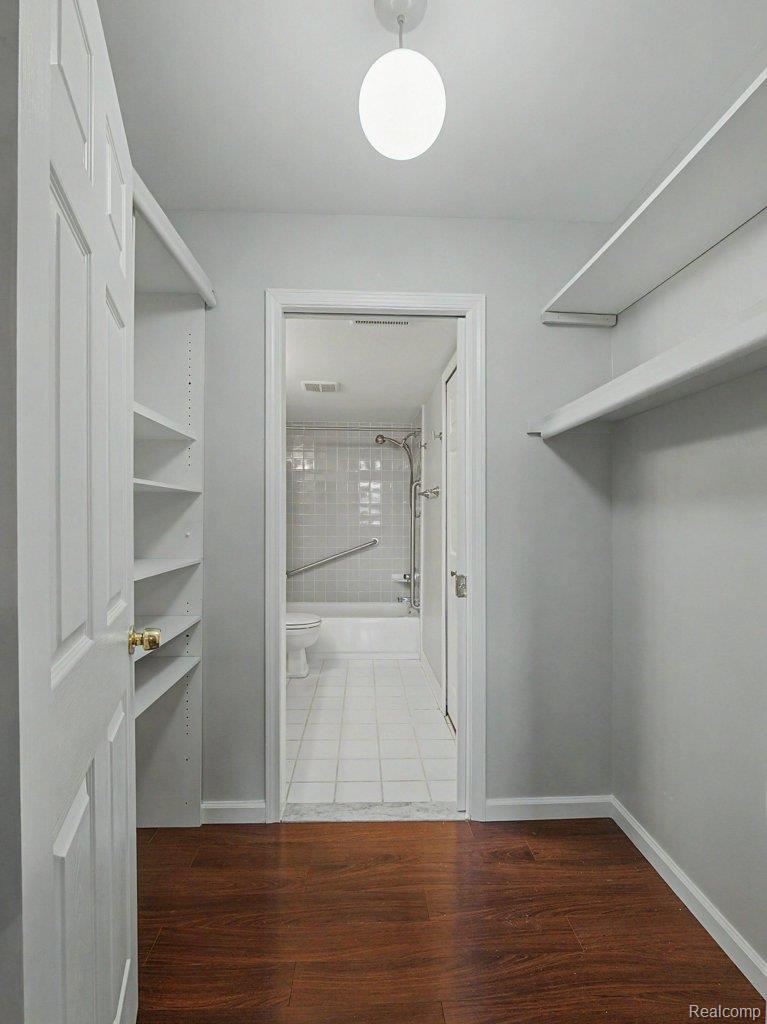 1974 Klingensmith Road, Unit 4 Bloomfield Hills, MI 48302 - Photo 20 of 35 Spacious walk-in closet featuring wood-finish flooring, built-in shelving, and an overhead light fixture