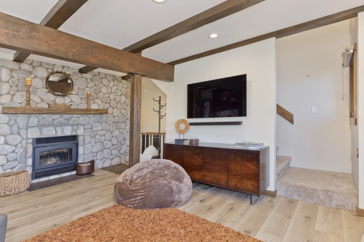 670 John Muir Road, Unit 1 Mammoth Lakes, CA 93546 - Photo 7 of 50 Living area with wood finished floors, beam ceiling, a fireplace, recessed lighting, and stairway