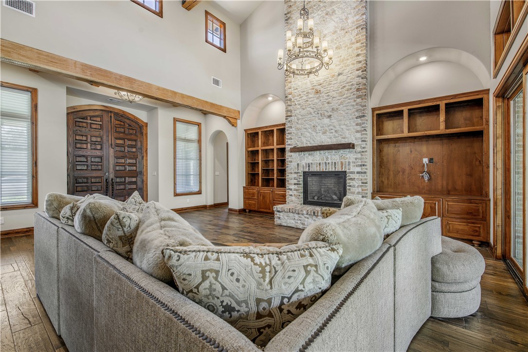 4207 Tuscany Court Bryan, TX 77802 - Photo 14 of 50 Living room featuring dark wood finished floors, built in features, a chandelier, a brick fireplace, and arched walkways