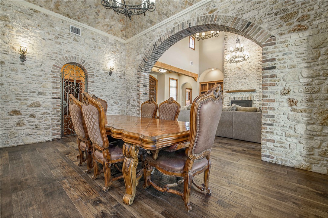 4207 Tuscany Court Bryan, TX 77802 - Photo 18 of 50 Dining area featuring a chandelier, a fireplace, a towering ceiling, dark wood-style flooring, and arched walkways