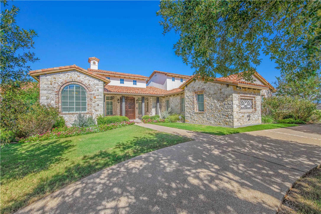 4207 Tuscany Court Bryan, TX 77802 - Photo 2 of 50 Mediterranean / spanish-style house with stone siding, a front yard, a tiled roof, and a chimney