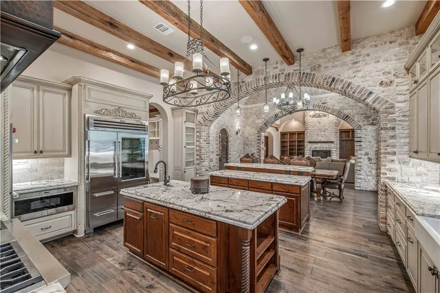 a large kitchen with kitchen island a stove a sink a dining table and chairs with wooden floor