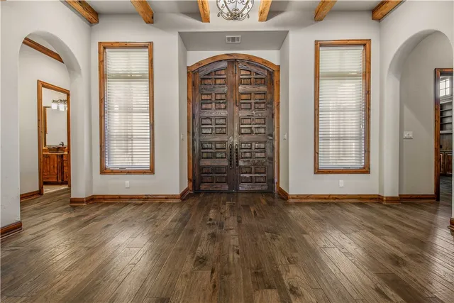 an empty room with wooden floor closet and windows