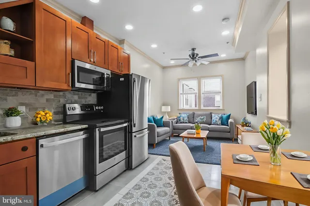 a open kitchen with stainless steel appliances granite countertop a stove refrigerator a sink dishwasher a dining table and chairs with wooden floor