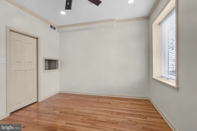a view of an empty room with wooden floor and a window