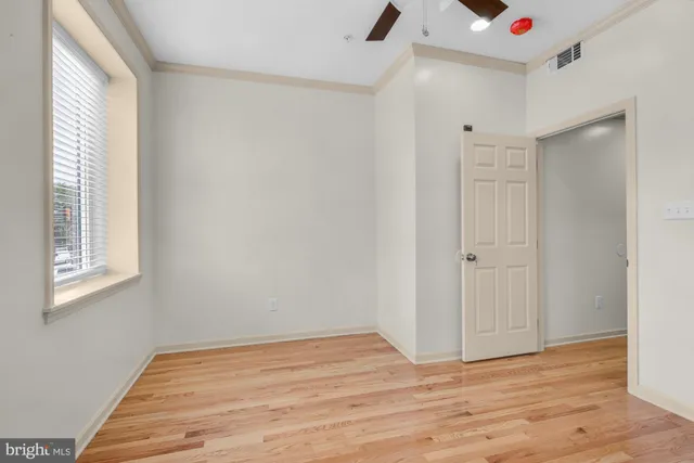 a view of empty room with wooden floor and fan