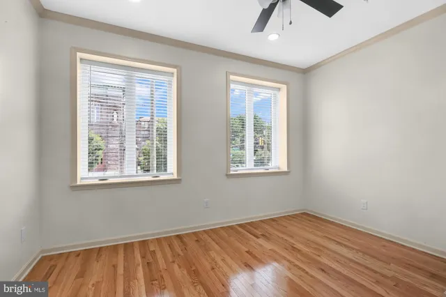 a view of empty room with wooden floor and fan