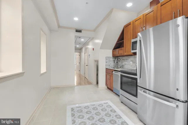 a kitchen with stainless steel appliances granite countertop a refrigerator a oven and white cabinets with wooden floor