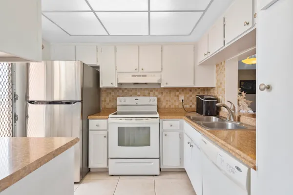 a kitchen with stainless steel appliances granite countertop a sink a stove a refrigerator a washer and dryer