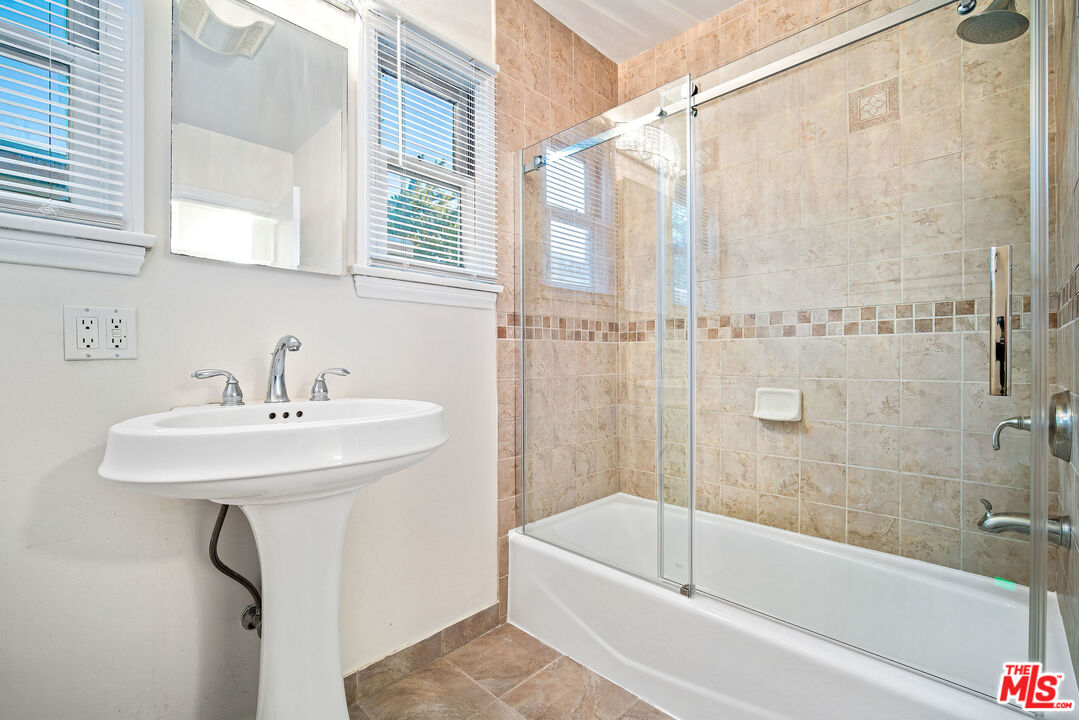 1924 Armacost Avenue Los Angeles, CA 90025 - Photo 27 of 33 a bathroom with a sink a mirror and a bathtub