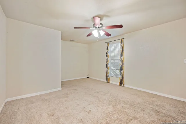 an empty room with windows and fan