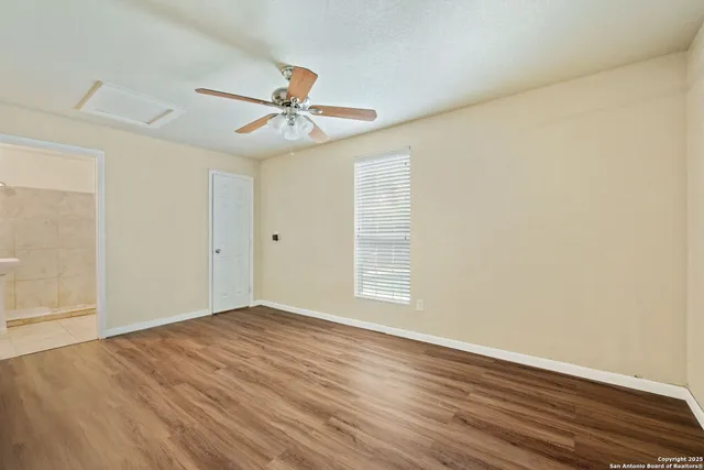 an empty room with wooden floor fan and windows