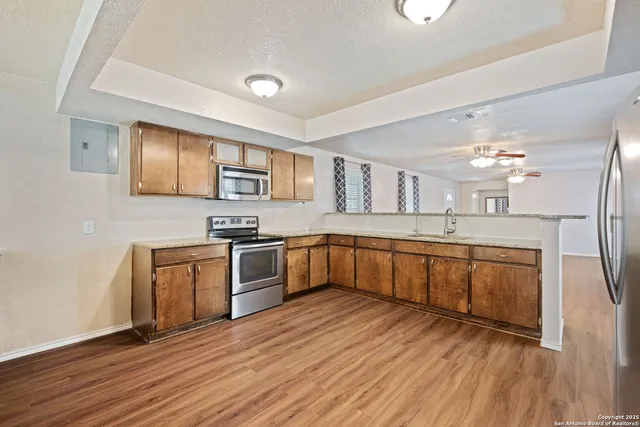 a large kitchen with stainless steel appliances granite countertop a lot of counter space and wooden floors