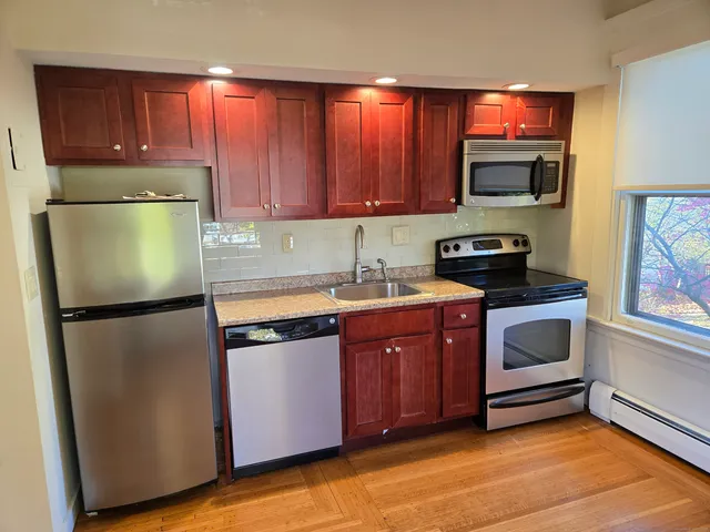 a kitchen with stainless steel appliances granite countertop a refrigerator stove a sink and dishwasher with wooden floor