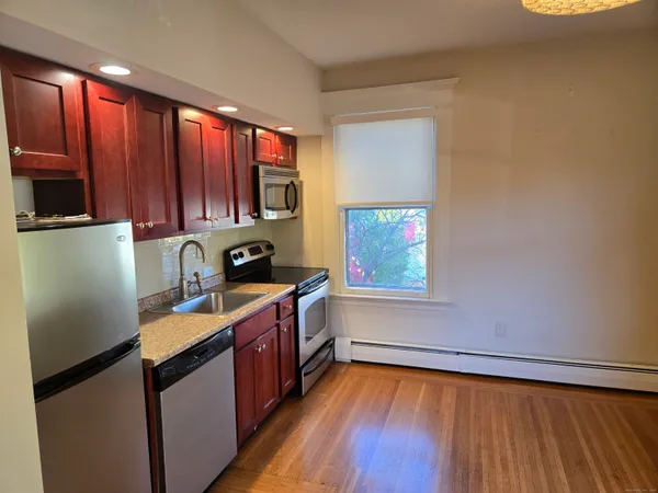 a kitchen with a sink wooden cabinets and a window
