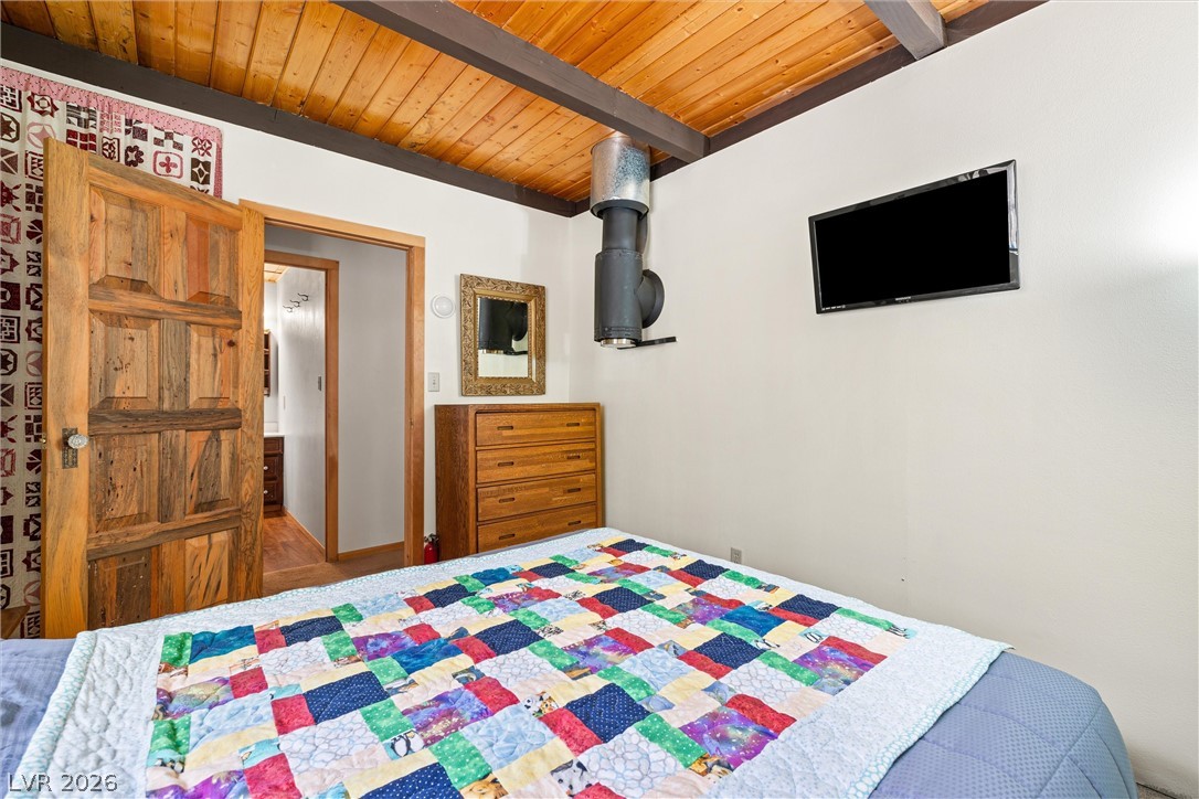 2146 Via Spes Nostra Street Mount Charleston, NV 89124 - Photo 22 of 33 A cozy bedroom with a unique wooden ceiling and a rustic wooden door leading to the primary bathroom.