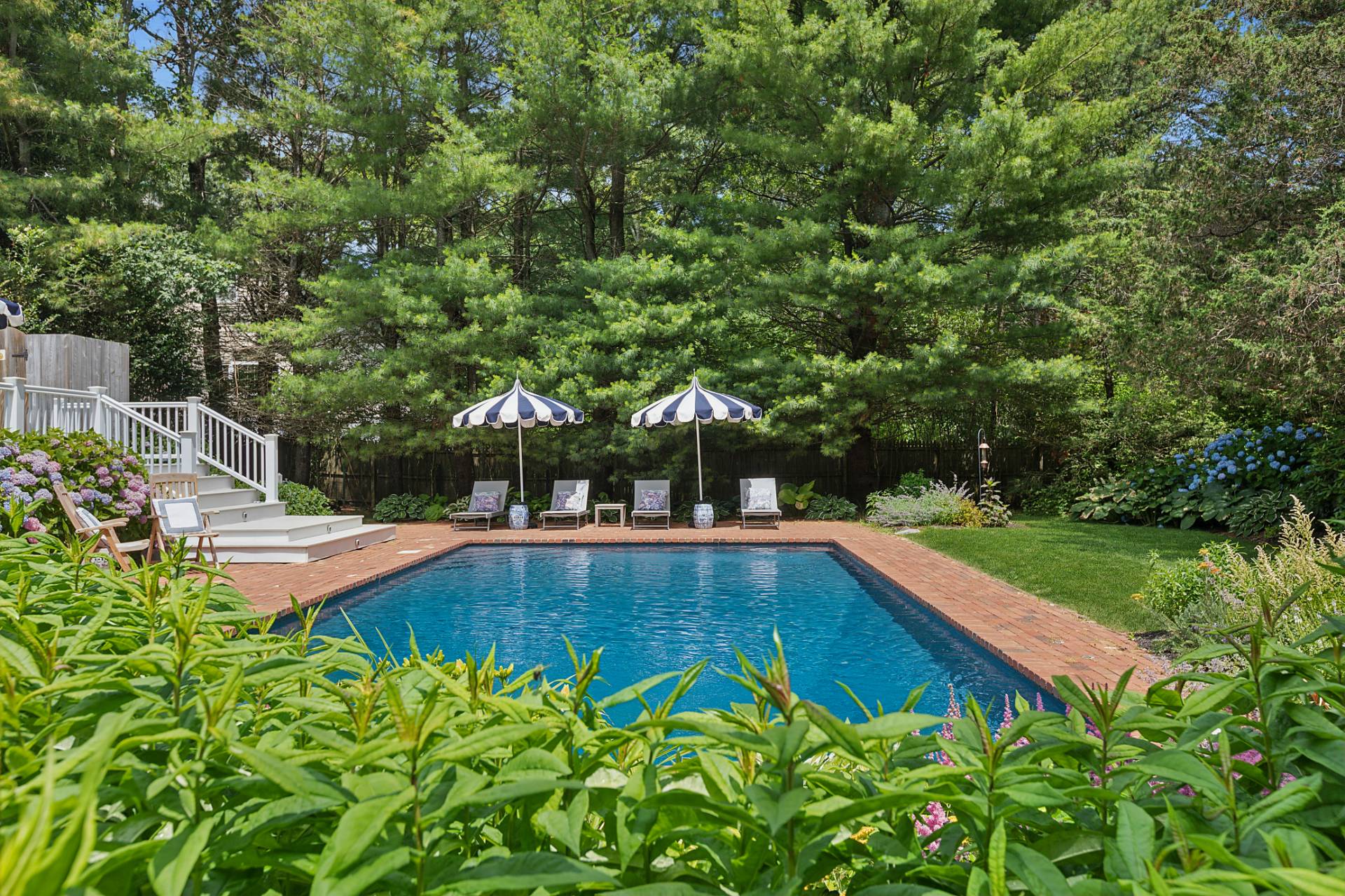 63 Whooping Hollow Road East Hampton, NY 11937 - Photo 21 of 25 a view of a swimming pool with a garden and deck