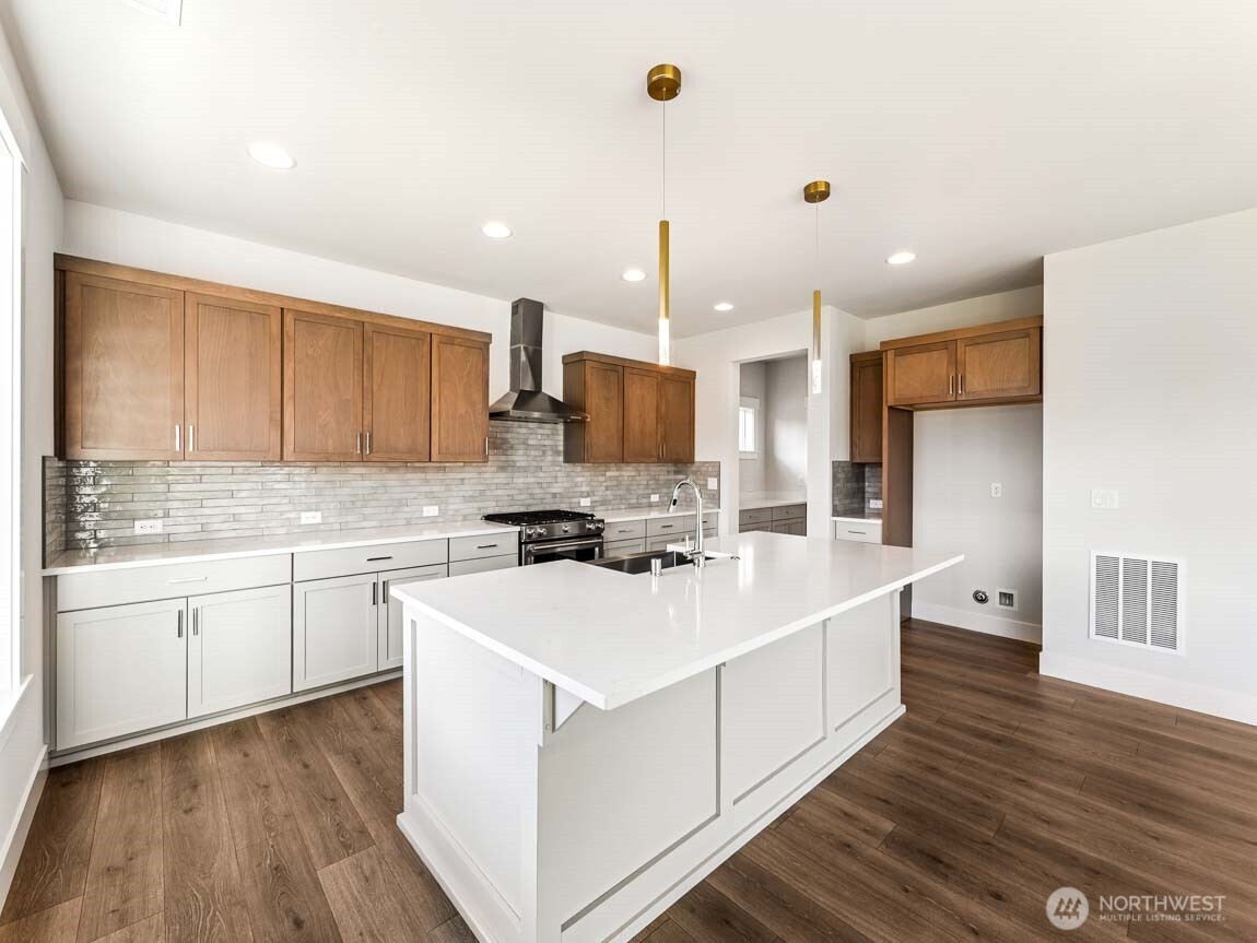 25012 181st Avenue Southeast, Unit 5 Covington, WA 98042 - Photo 11 of 34 a large white kitchen with a stove top oven a sink dishwasher and a refrigerator with wooden floor