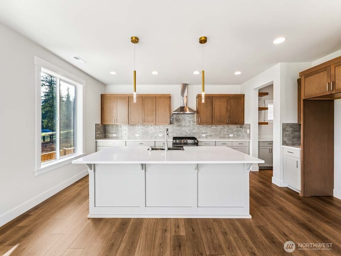 25012 181st Avenue Southeast, Unit 5 Covington, WA 98042 - Photo 8 of 34 a large white kitchen with kitchen island a sink wooden floor and stainless steel appliances
