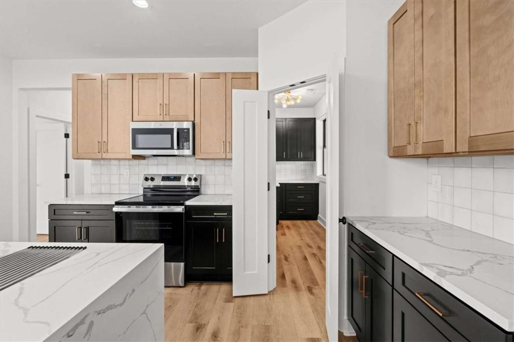 409 Lively Road Waco, GA 30182 - Photo 15 of 50 a kitchen with kitchen island granite countertop a stove top oven a sink dishwasher and white cabinets with wooden floor
