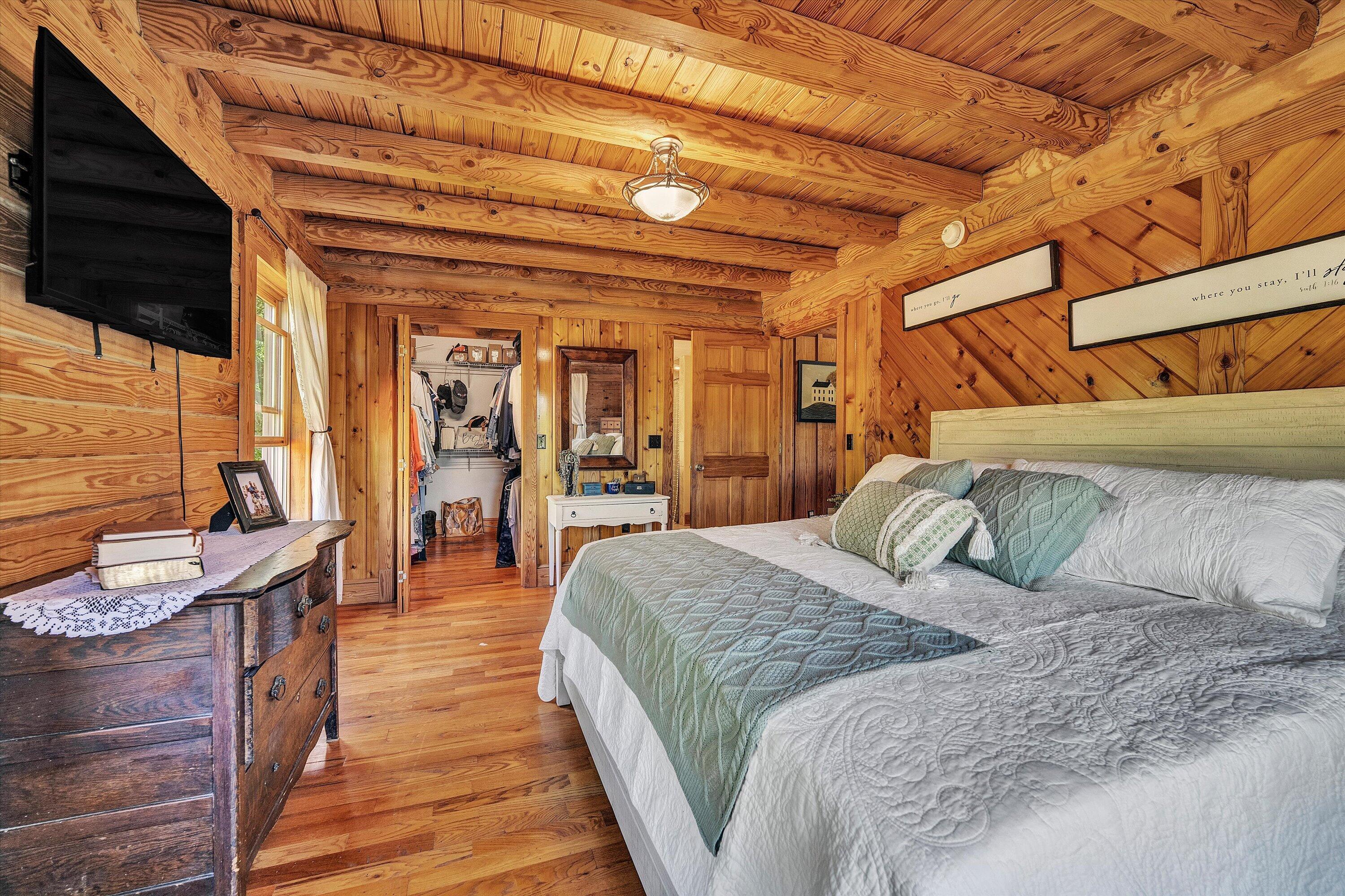 180 Thompson Ridge Circle Ferrum, VA 24088 - Photo 25 of 74 a spacious bedroom with a bed a mirror and a flat screen tv