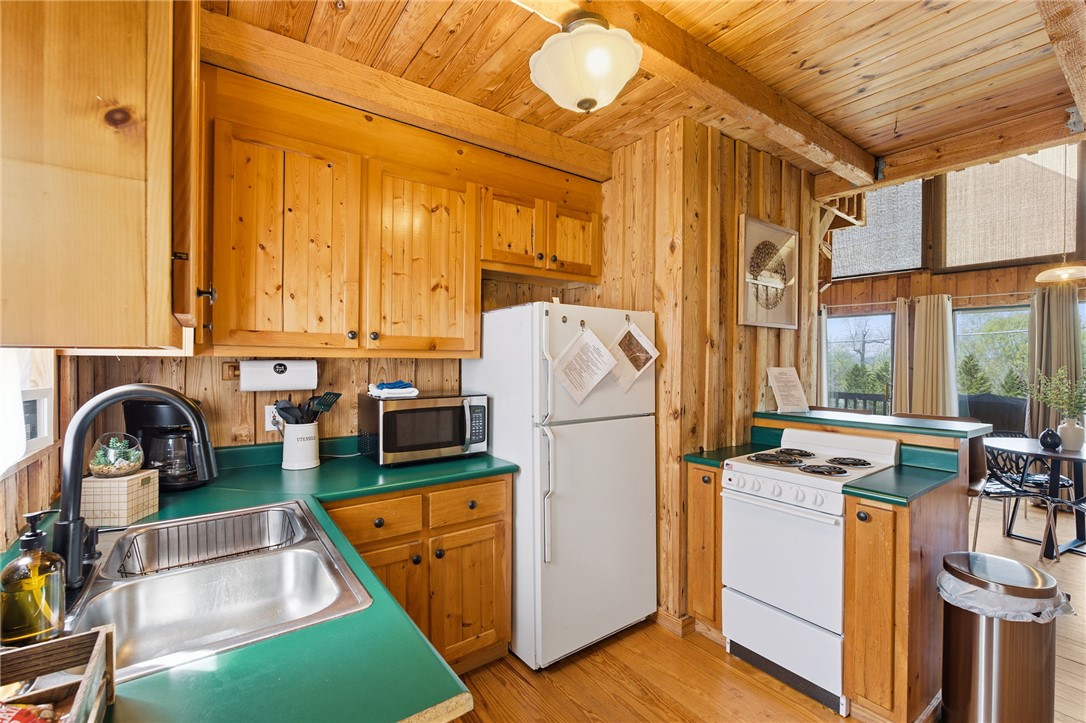 1 Kitty Hawk Lane Six Mile, SC 29682 - Photo 15 of 46 This cozy kitchen features a classic aesthetic with wooden paneling and bright green countertops.